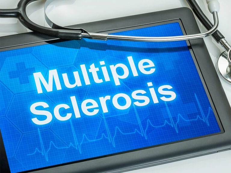 A tablet screen displays the text "Multiple Sclerosis" with a stethoscope resting on top.